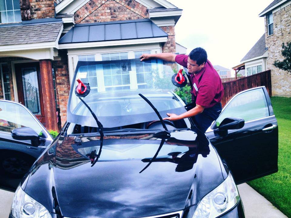 A man is raising a car window, focusing on the mechanism with a determined expression.