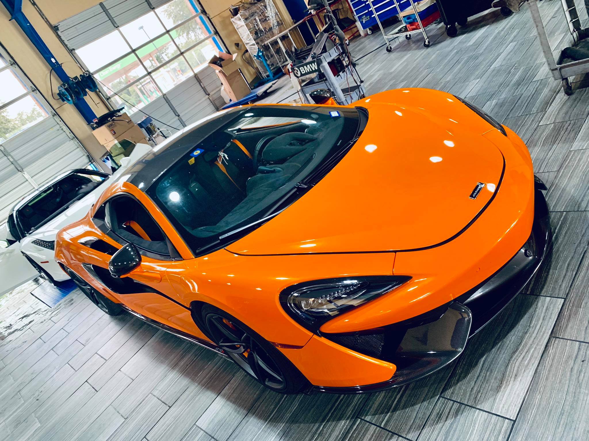 An orange McLaren car parked in a spacious garage, showcasing its sleek design and vibrant color.